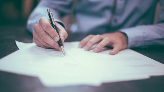 Man writting on paper on a desk