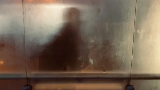 Image of a person's shadow behind a foggy, obscure window at night