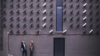 two women looking at surveillance camera art installation