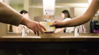 Hand passing a small wrapped item to another hand