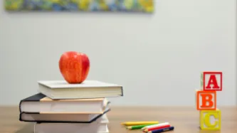 school desk with books, pencils, children's toys and an apple